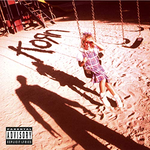 Child on a swing, long shadow, "Korn" graffiti, parental advisory label.