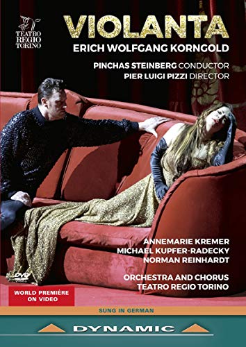 A man in black stands over a woman in a gold dress on a sofa.