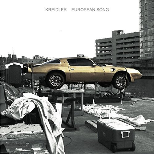 "Vinyl album cover: gold car on a rooftop with cityscape background."