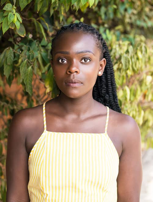 Young Black woman with braided hair and a striped yellow top.