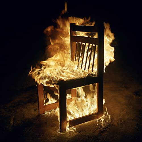 Burning wooden chair against a dark background, album cover art.