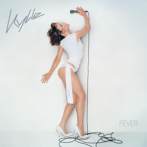 Kylie Minogue in white dress singing into a microphone, album cover.