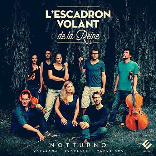 Group of seven musicians posing with string instruments in front of a willow tree.