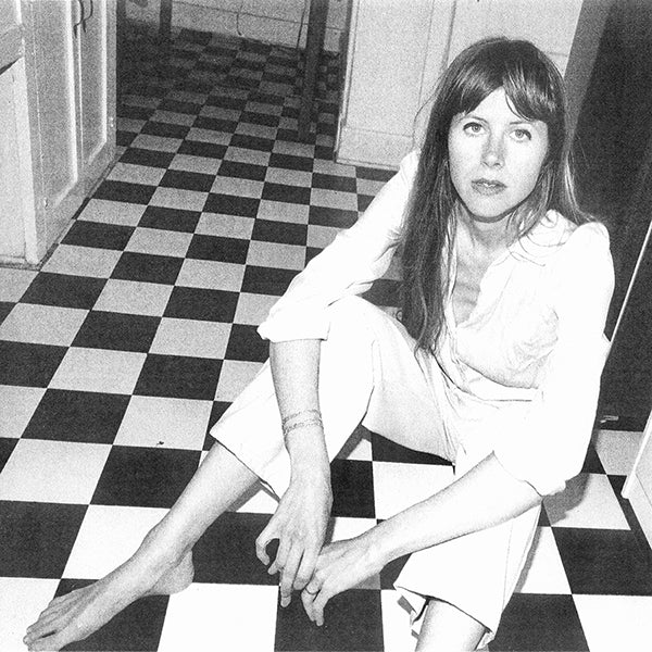 Black and white photo of Lael Neale sitting on a checkered floor.