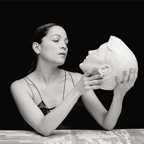 Black and white portrait of a woman holding a plaster face sculpture.