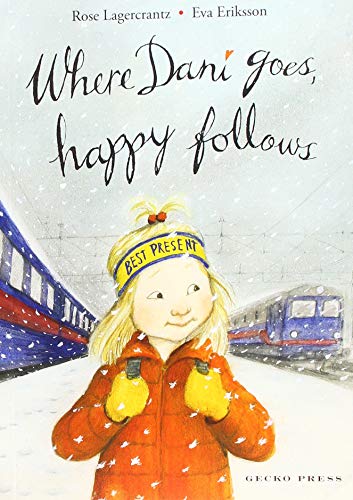 Child in orange coat stands near a blue and white train in snow.