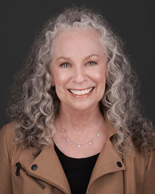 Portrait of a smiling woman with curly gray hair and a brown jacket.