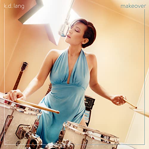 k.d. lang in a blue dress playing drums in a recording studio.