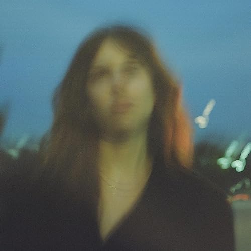 Soft-focus portrait of a person with long hair against a blurred blue background.