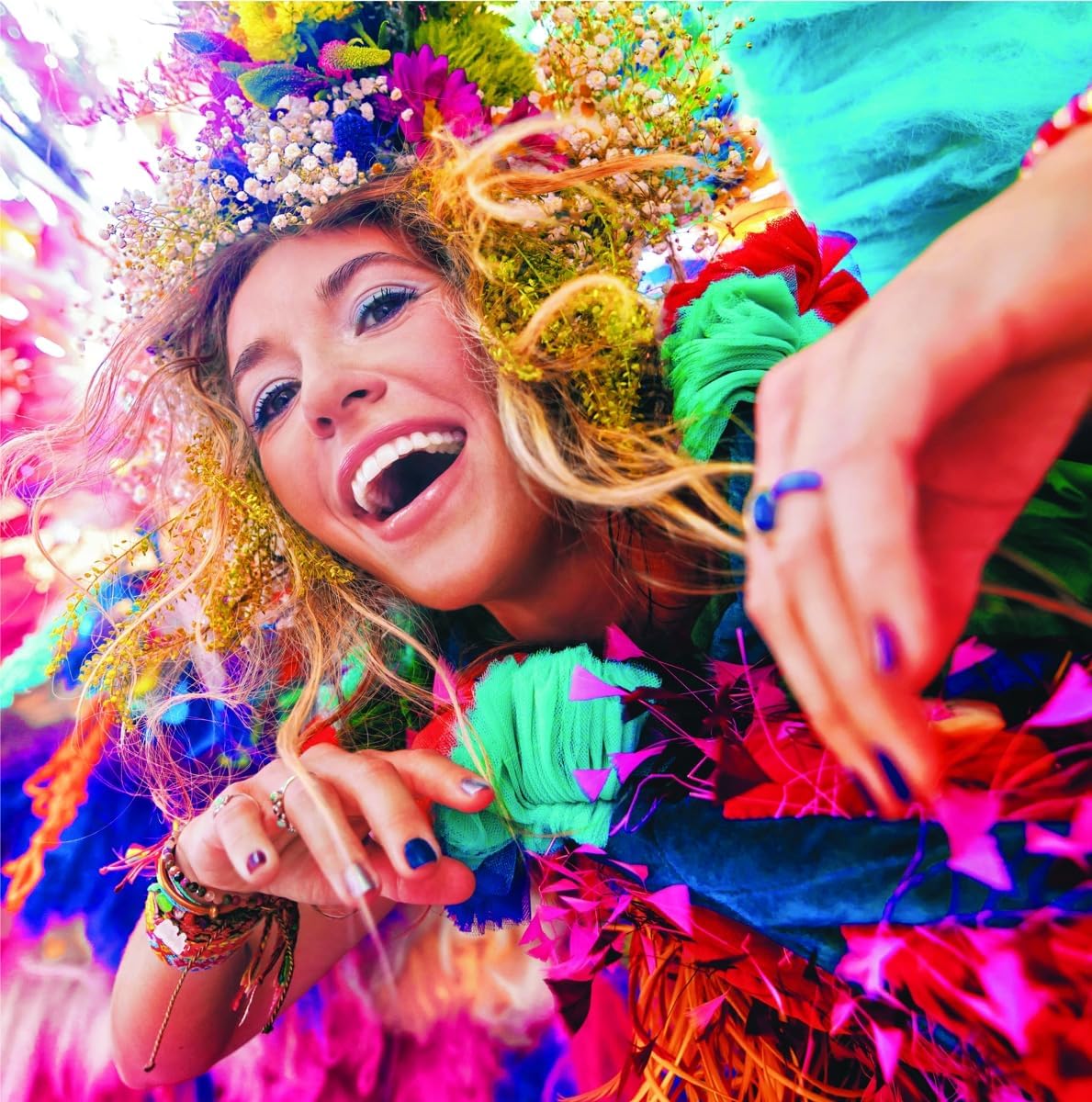 Lauren Daigle smiling, wearing a floral crown and colorful outfit, with brightly lit background.