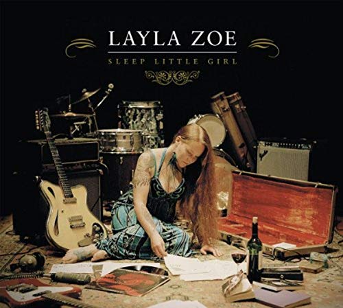 CD cover: Layla Zoe sits amongst musical instruments and scattered papers.