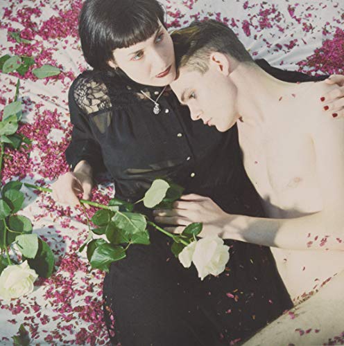 Couple embracing amidst scattered rose petals and white roses.