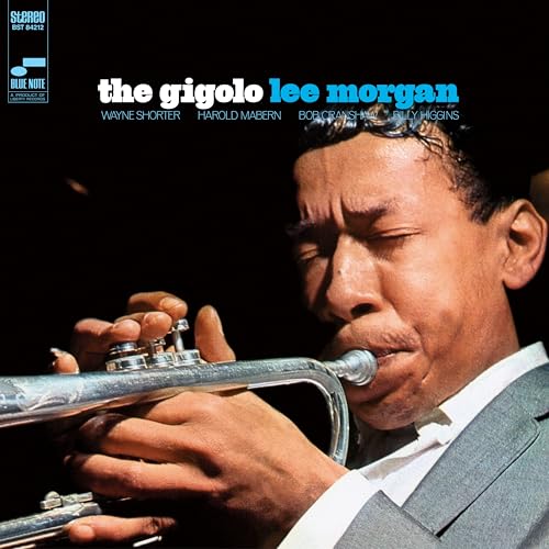 Lee Morgan plays the trumpet in this close-up portrait on a dark background.