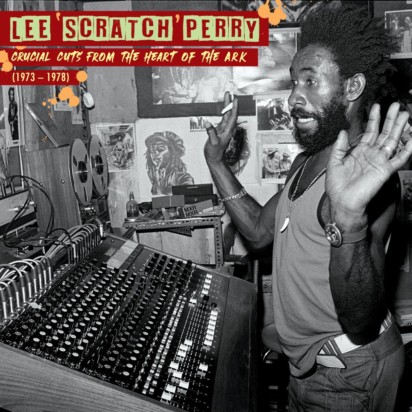 Lee Scratch Perry in a recording studio with a mixing console and reel-to-reel tape.