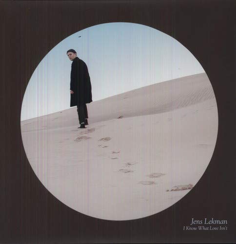 Vinyl record cover: man in black coat on sandy dunes.