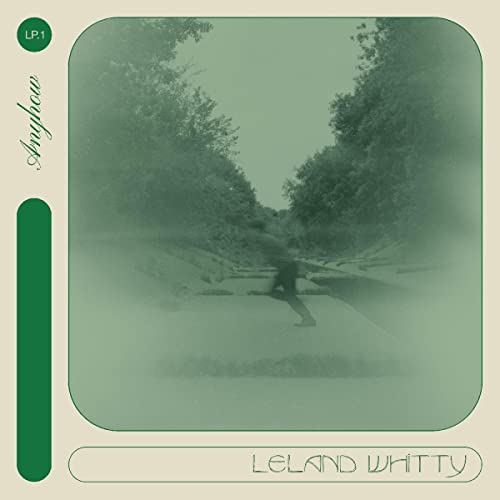 CD cover: blurry green landscape with a figure walking down a road.