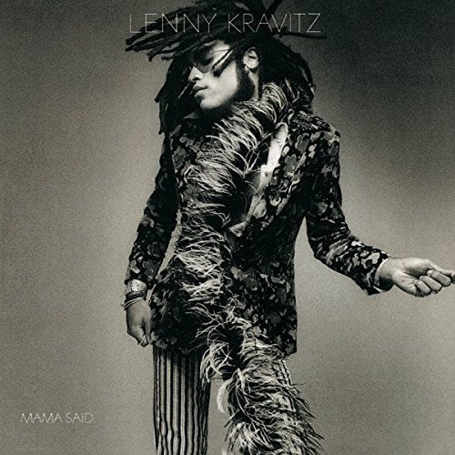 Black and white portrait of Lenny Kravitz with dreadlocks wearing a feathered jacket.