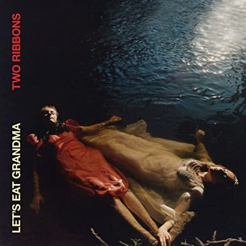 Two people in red and white dresses floating in dark water.