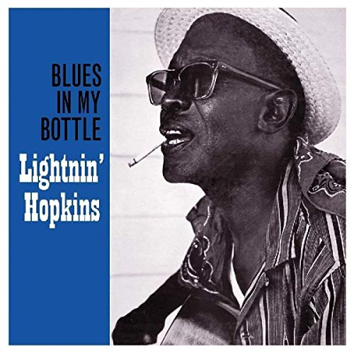 Black and white portrait of Lightnin' Hopkins wearing a hat and glasses with cigarette.