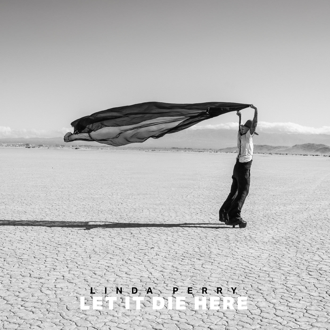Black and white album cover featuring a person with flowing fabric in a desert.