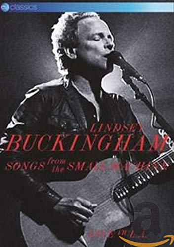 Lindsey Buckingham singing and playing acoustic guitar on stage in a black and white photo.