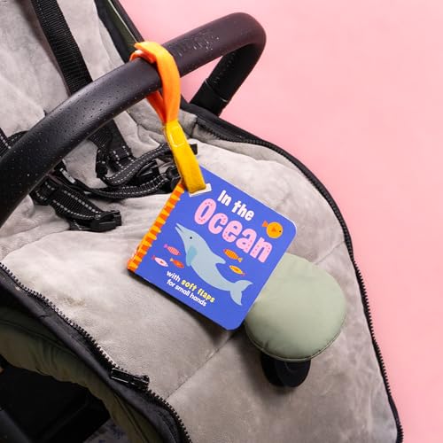 Blue children’s book “In the Ocean” with a dolphin, hanging from a stroller.