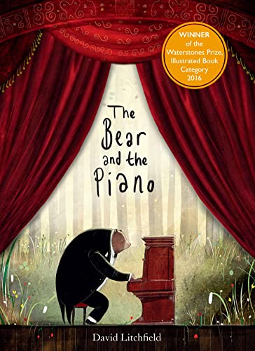 Bear in a suit plays a red piano on a stage.