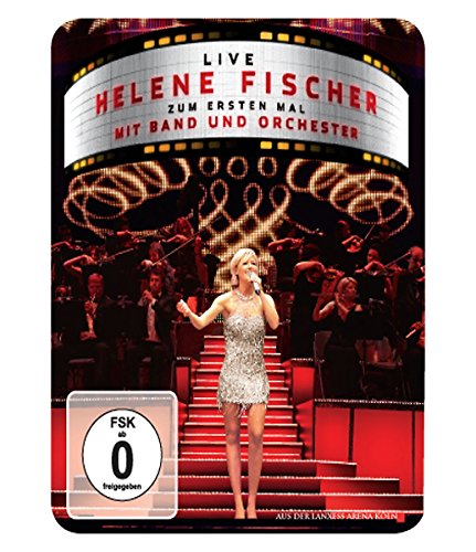 Helene Fischer performing on stage with an orchestra, wearing a silver dress.