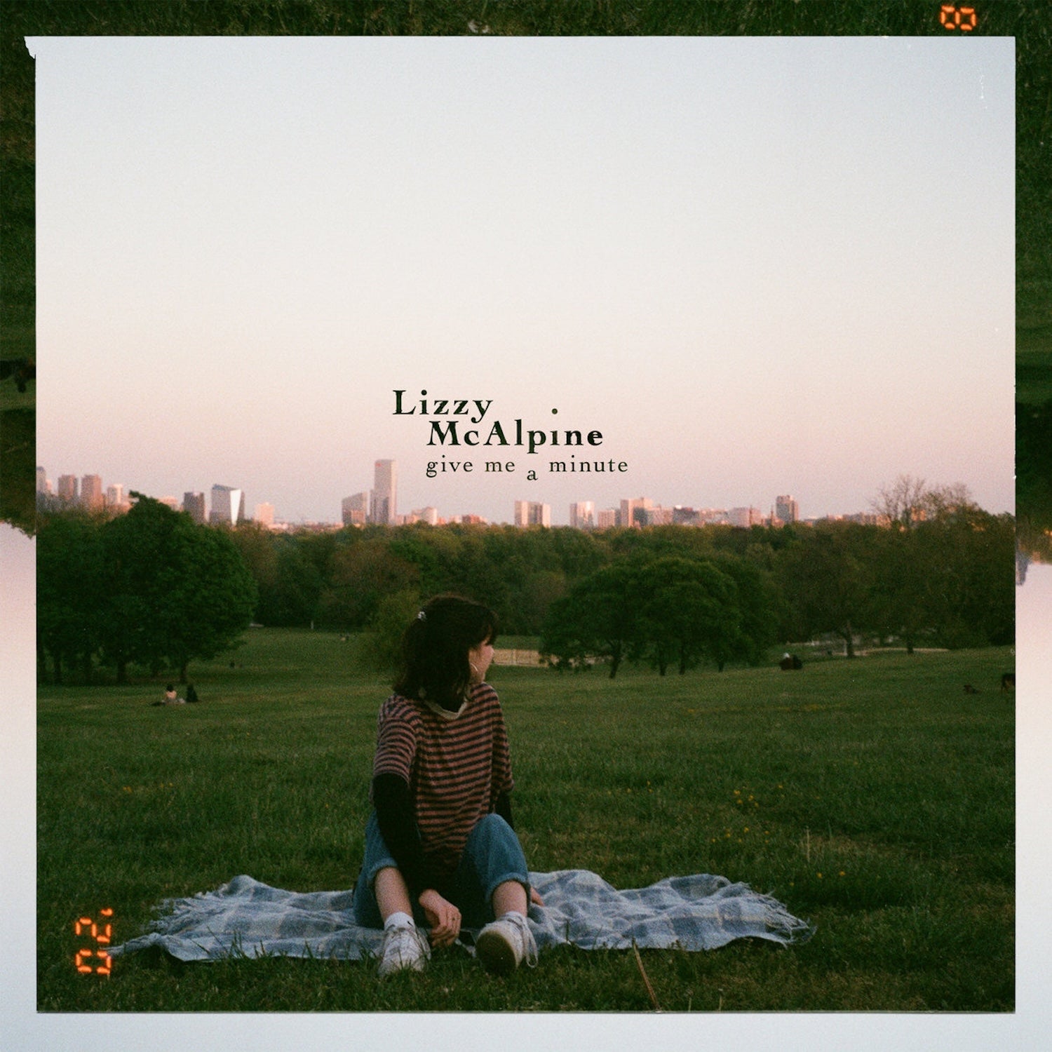 CD cover: Lizzy McAlpine sits in a park with a city skyline.