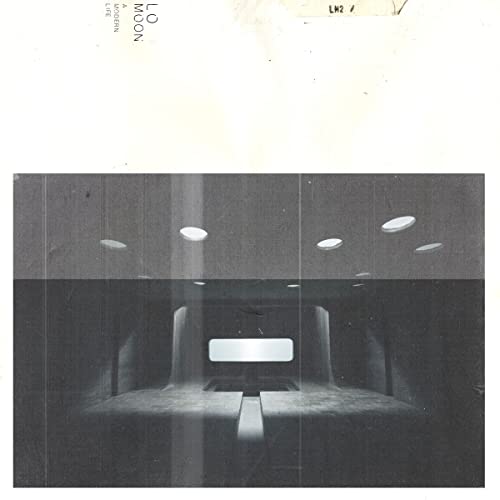 Black and white photo of a dark room with a glowing screen and ceiling lights.