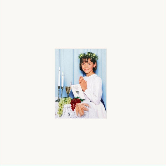 Girl in white dress with flower crown, praying at altar.