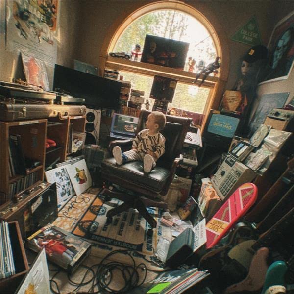 A cluttered room with a young person seated among vinyl records.