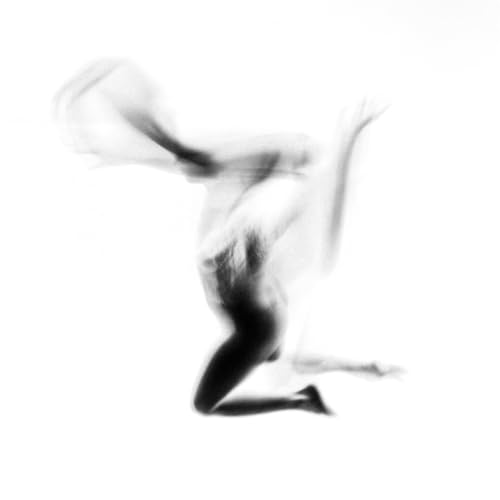 Blurred black and white image of a figure in dynamic motion.