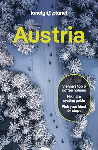 Aerial view of skiers on a snowy path through a pine forest in Austria.
