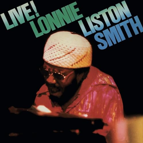 Lonnie Liston Smith wearing a knit cap and sunglasses while playing a keyboard.