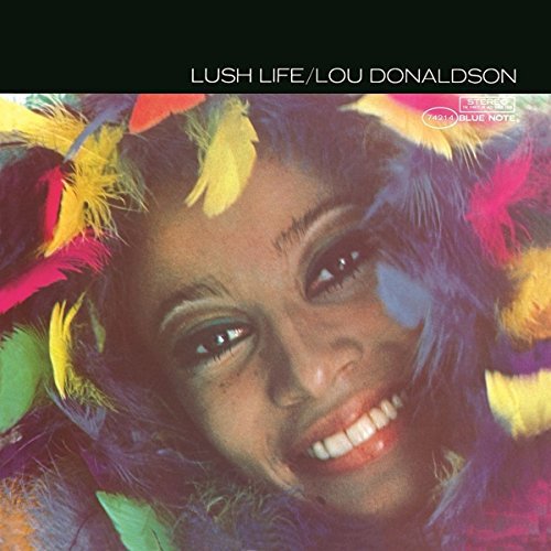 Album cover featuringS featuring a smiling woman surrounded by colorful feathers.