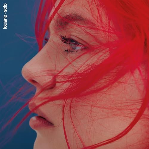 Close-up of a woman with red hair against a blue background.