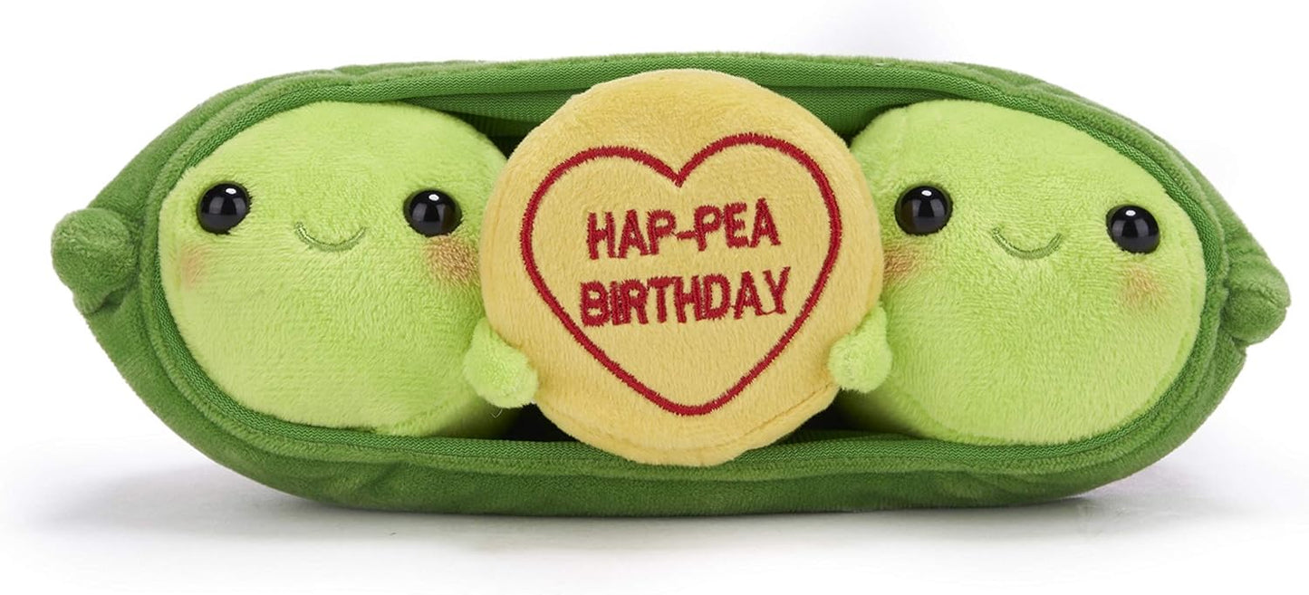 Two plush green peas in a pod holding a yellow heart-shaped birthday sign.