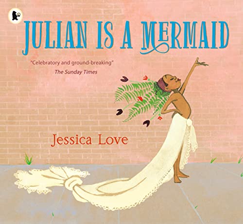 A child wearing a long white skirt and fern headdress stands against a brick wall.
