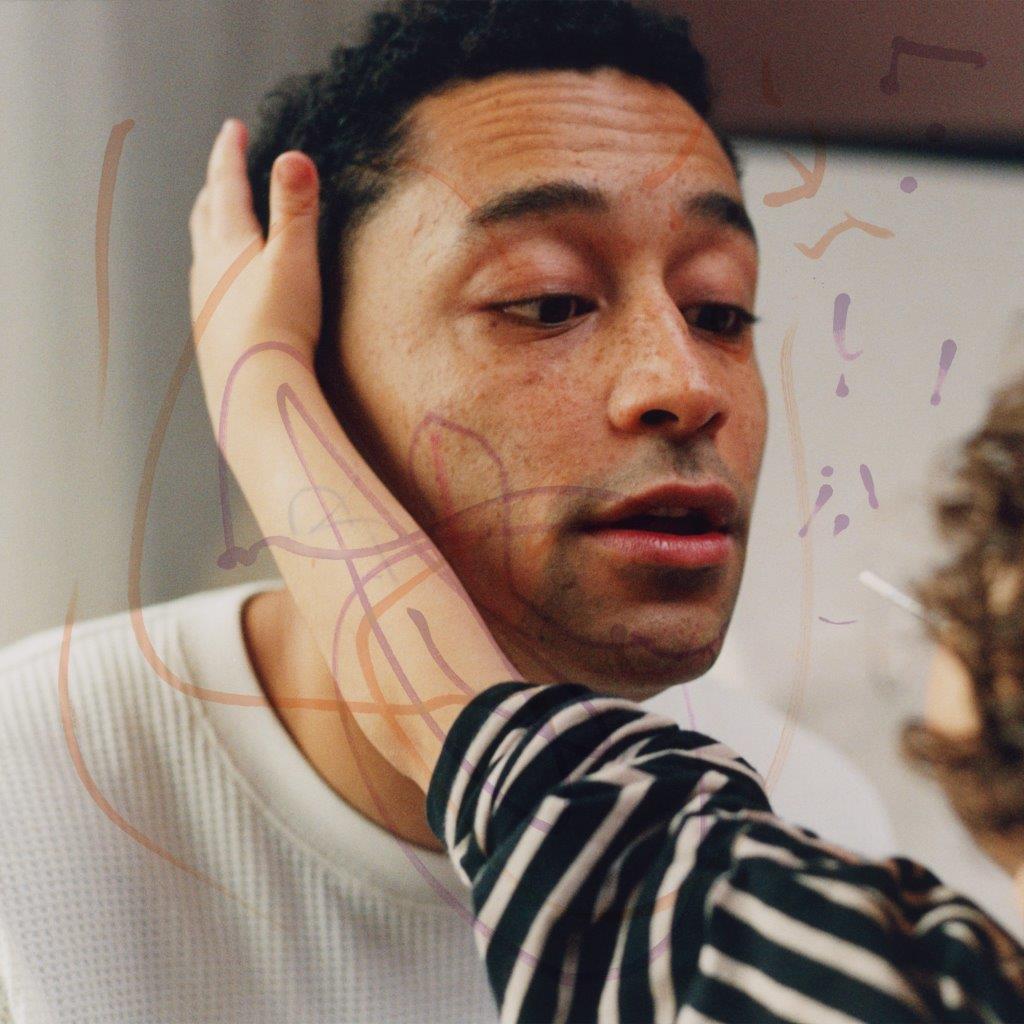Close-up of Loyle Carner with arm tattoos, abstract purple scribbles.