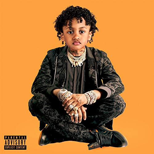 Young man with curly hair, jewelry, and patterned clothing, on orange background.