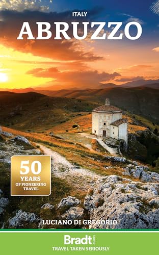A stone church sits on a grassy hill at sunset under a golden sky.