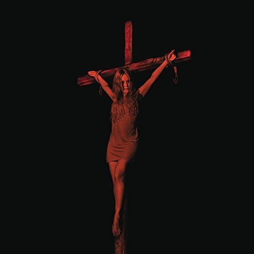 Woman on a wooden cross, bathed in red light, dark background.