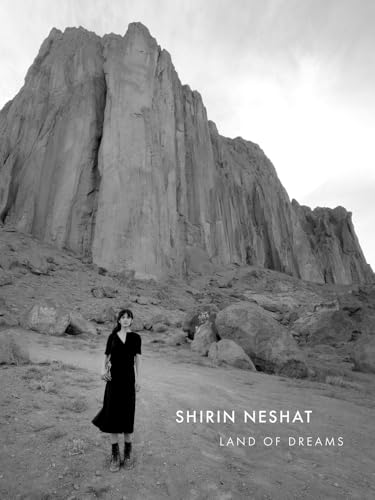 Black and white photo of a woman before a large rock formation.