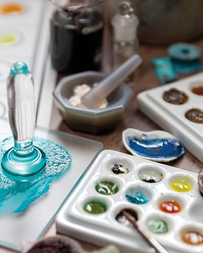 Art supplies including a glass muller, mortar and pestle, and paint palettes with pigments.