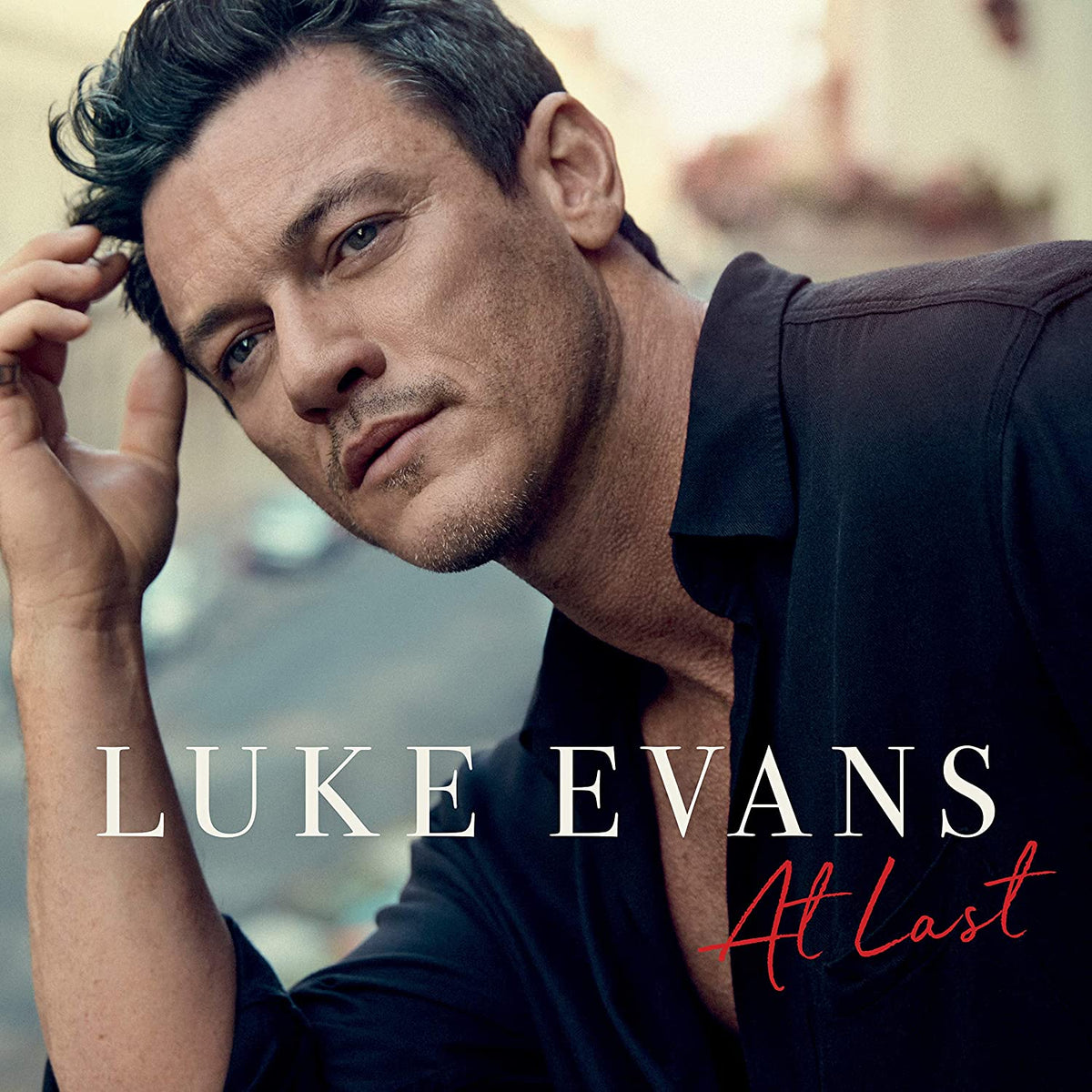 "Album cover featuring Luke Evans in a black shirt, with text 'Luke Evans At Last'."