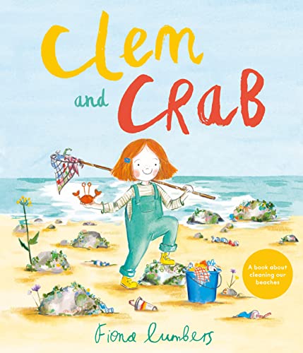 A girl with red hair holds a crab on a beach with litter.