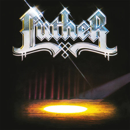 Shiny metallic Luther logo above a stage with a bright spotlight on dark floor.