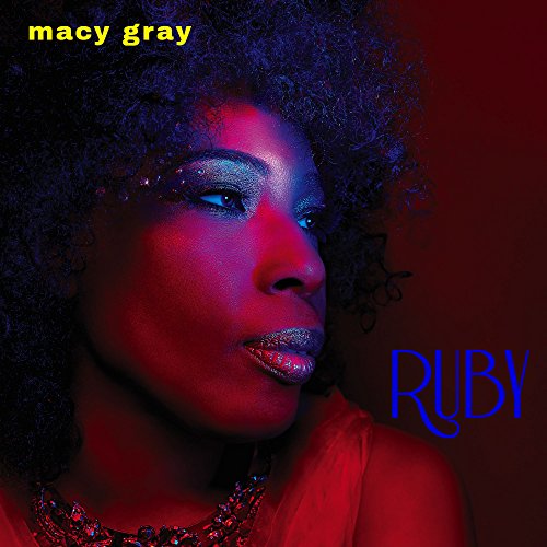 Close-up portrait of Macy Gray with dramatic red and blue lighting on dark background.
