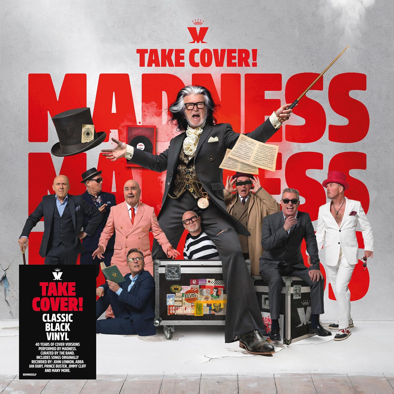 The band Madness posing in formal attire against a large red logo background.